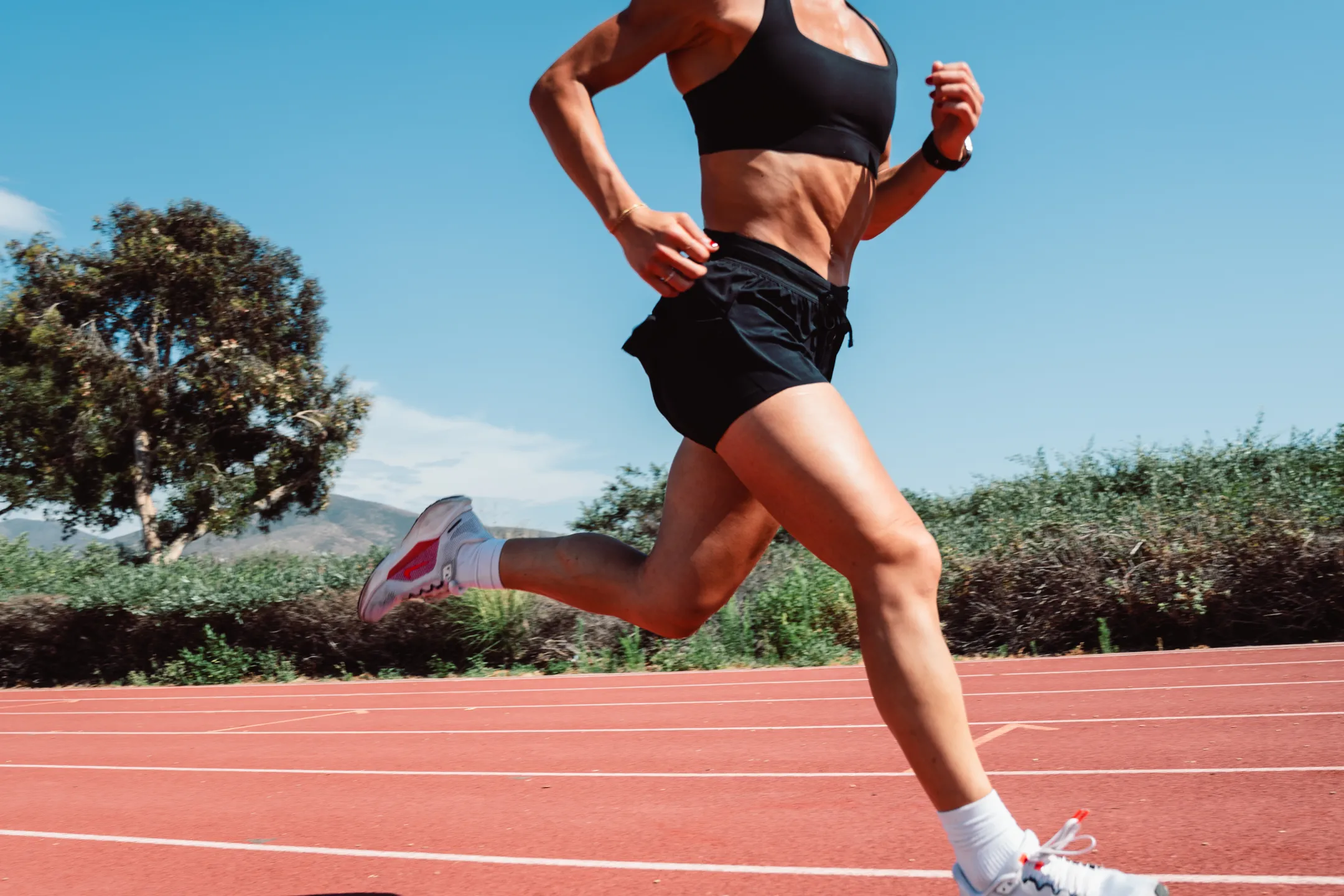 Runner in full flight on the track, watch on wrist